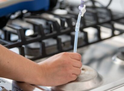 Image of a scientists taking a natural gas sample from a kitchen stove.