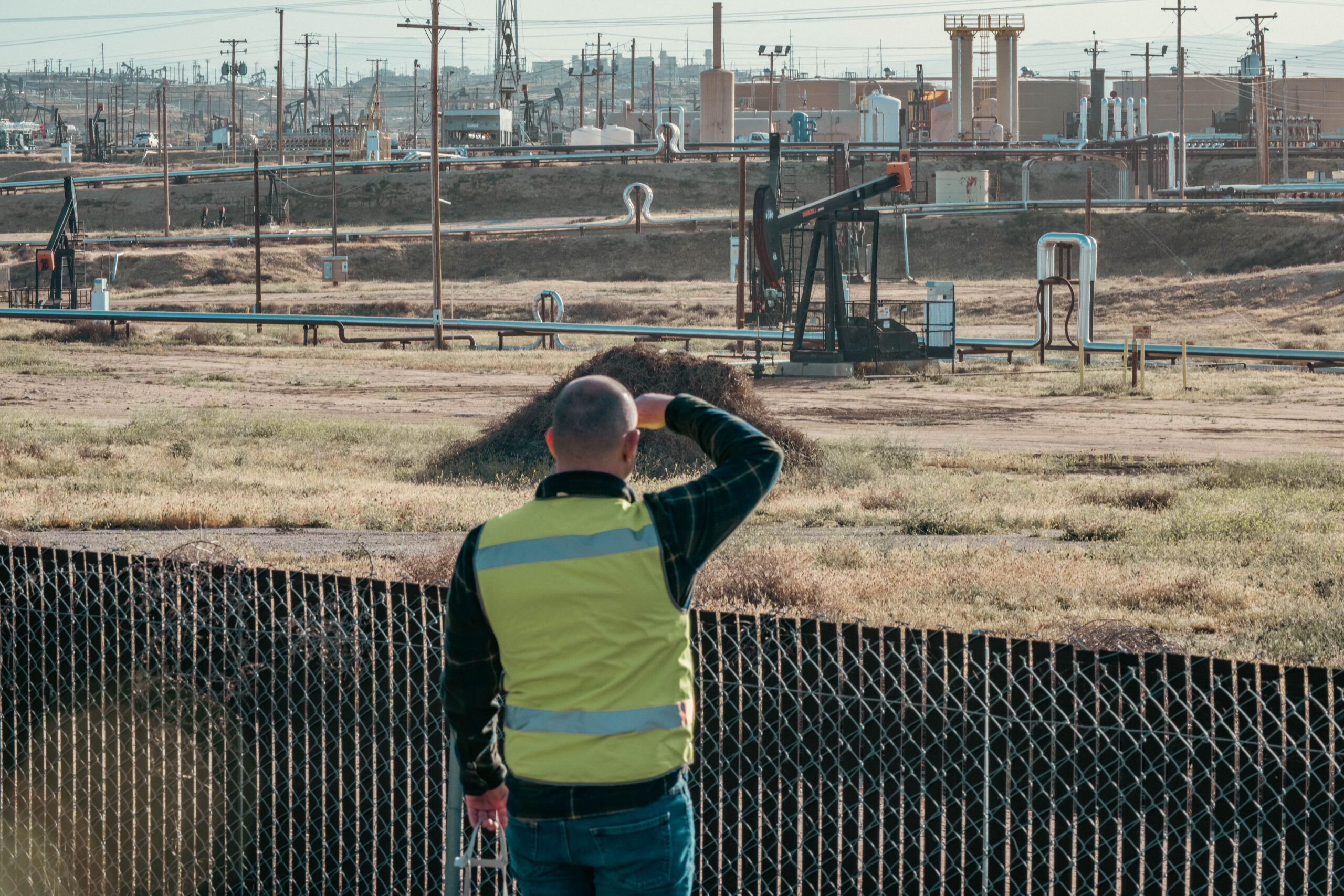 A researcher observes oil and gas equipment from the fenceline.