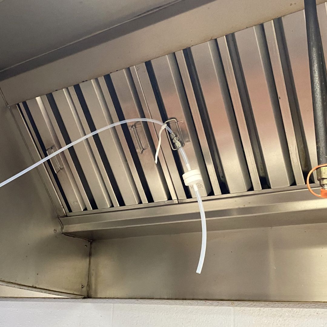 A line of plastic hosing secured inside a ventilation hood.