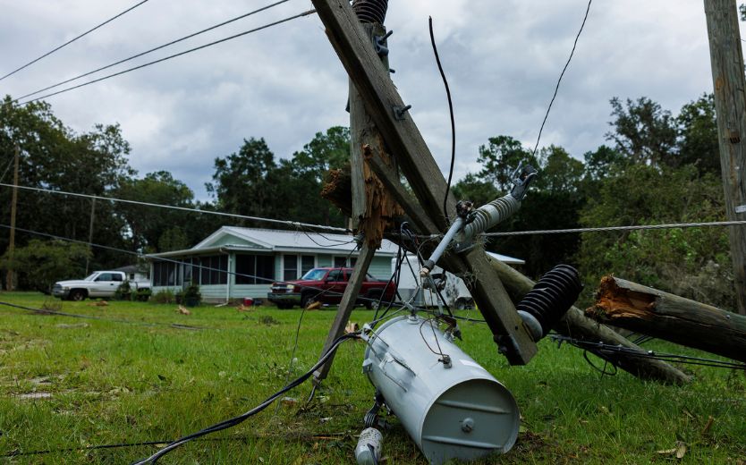 Image of a downed power line on the lawn of a rural home with two cars in the driveway.