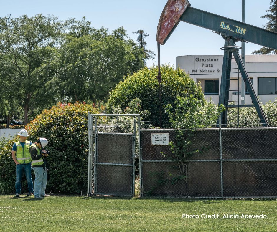 Image of two researchers taking FLIR imaging at a pump jack. 